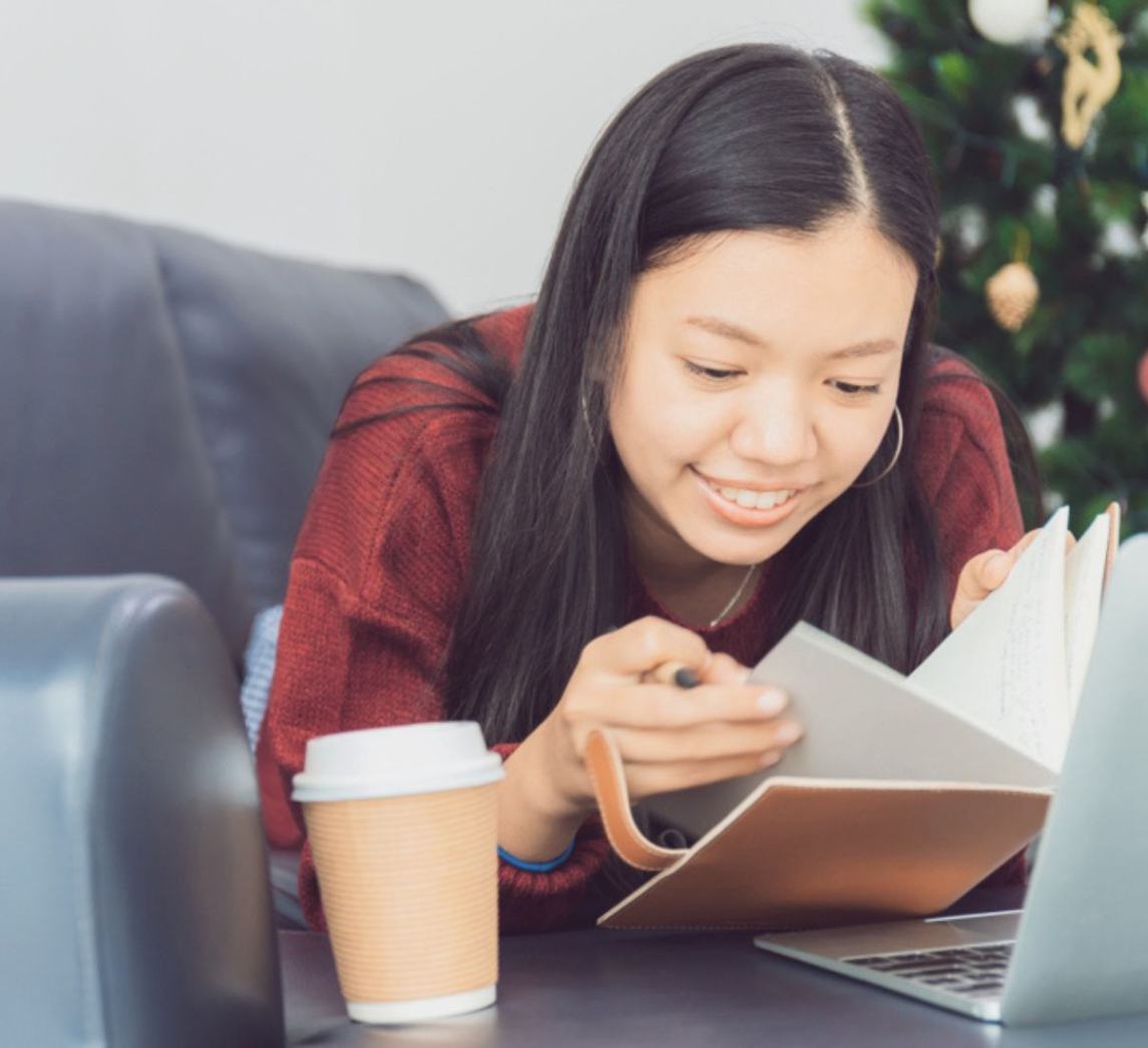 Asian girl reading a notebook at home.
