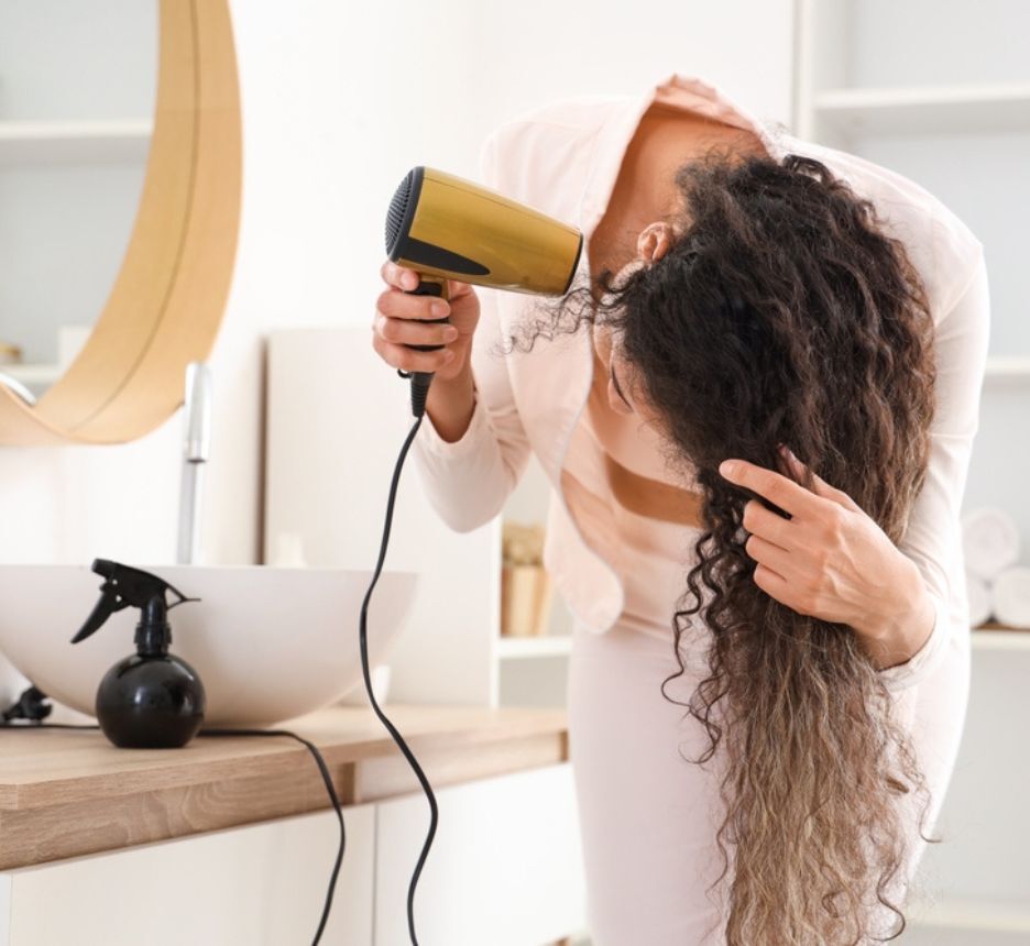 Woman blow drying her curly hair.