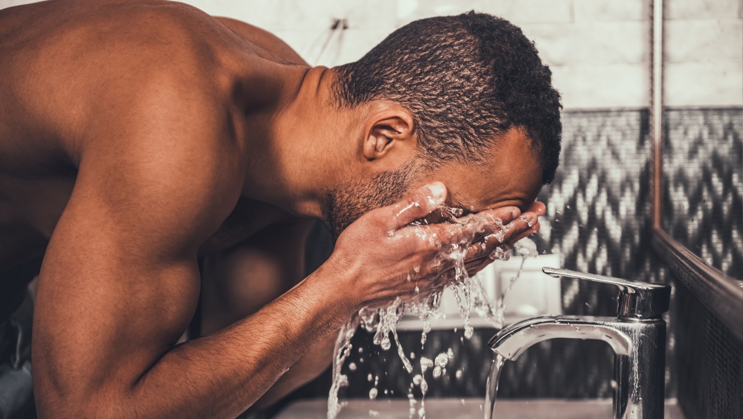 Young man washing his face with body wash