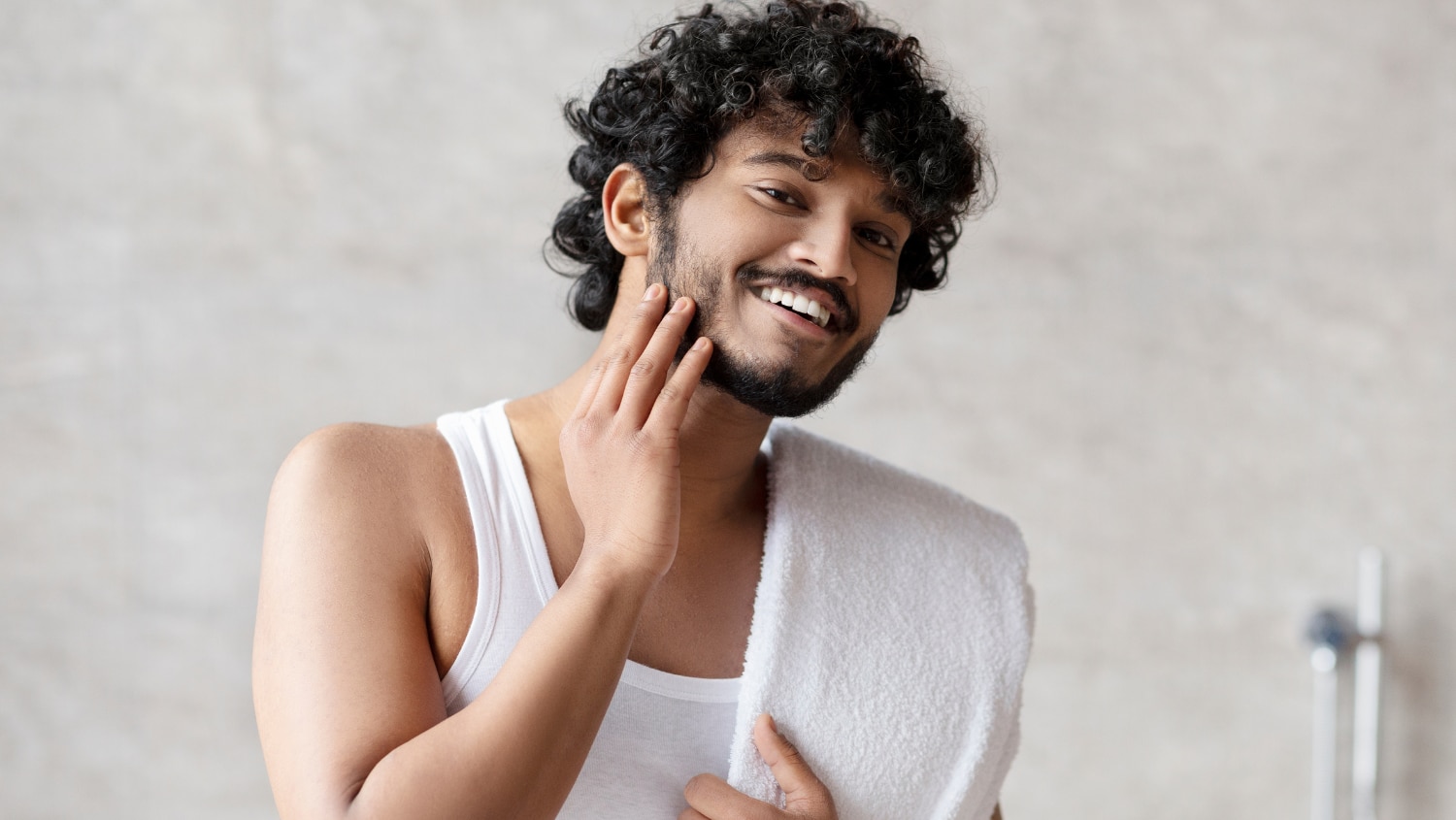 Young Gen Z male touching his beard after having a shower