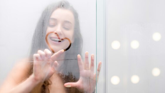 Woman in the shower drawing a heart shape on the shower glass