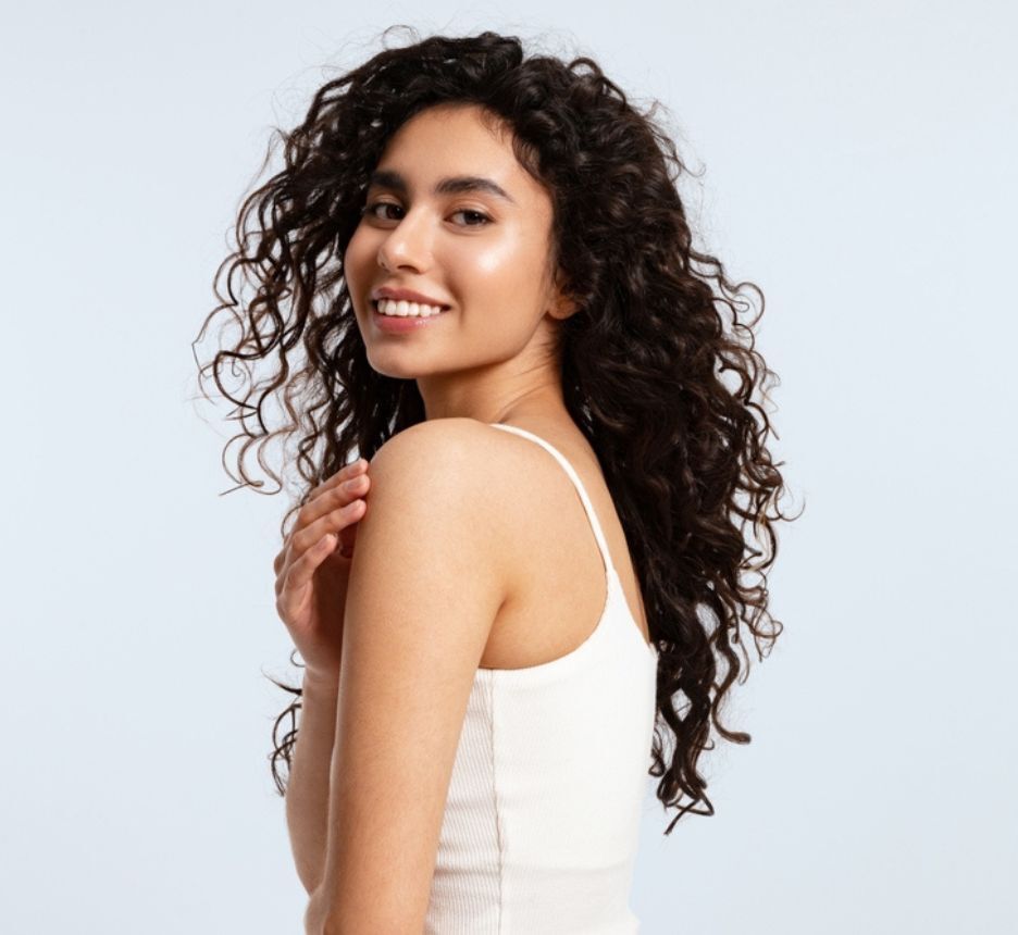 tóc xù tóc xù cho mặt góc cạnh cô gái mặc áo hai dây màu trắng đang cười tươi