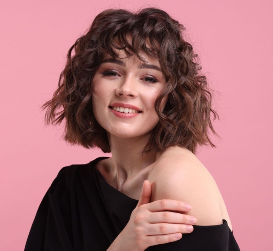 tóc xù tóc xù mì ngắn cô gái cười tươi chụp ảnh trên nền màu hồng.