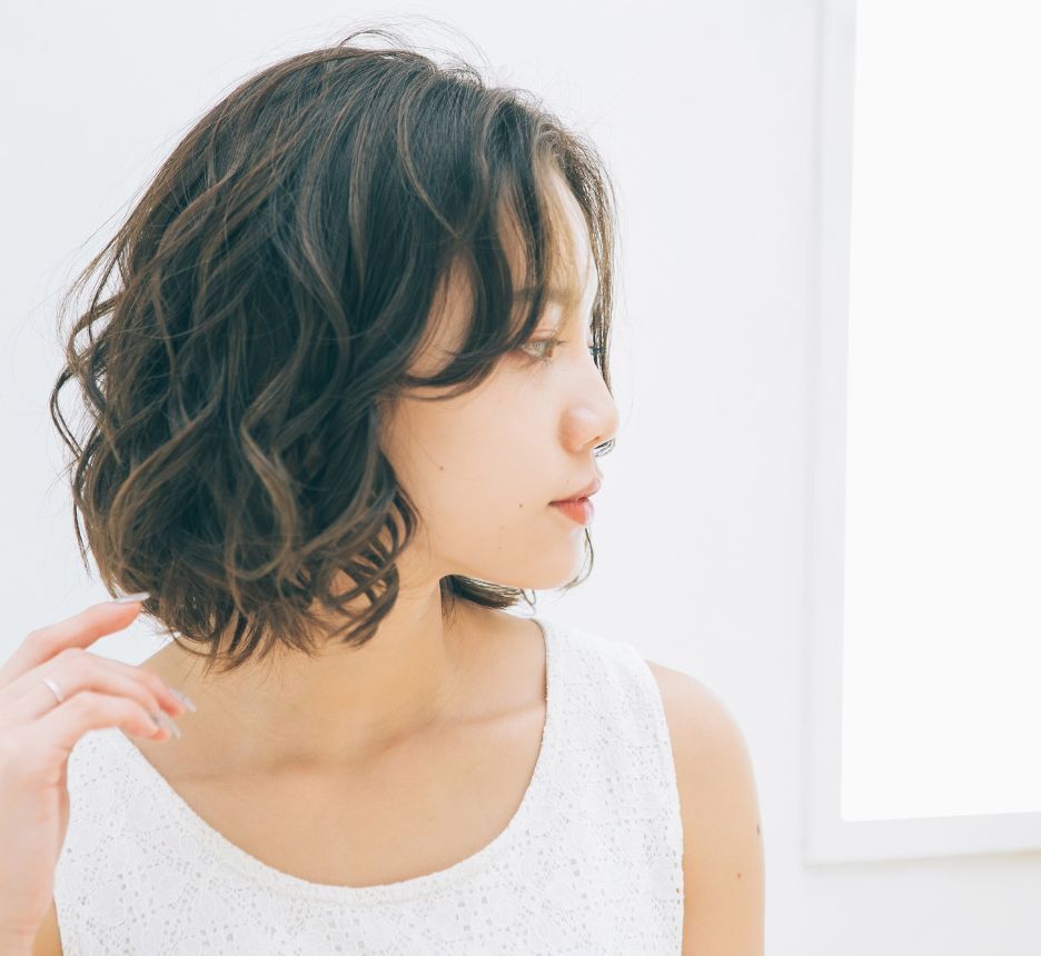 tóc xù tóc xù uốn lọn cô gái mặc áo ba lỗ màu trắng và đang nhìn sang bên phải