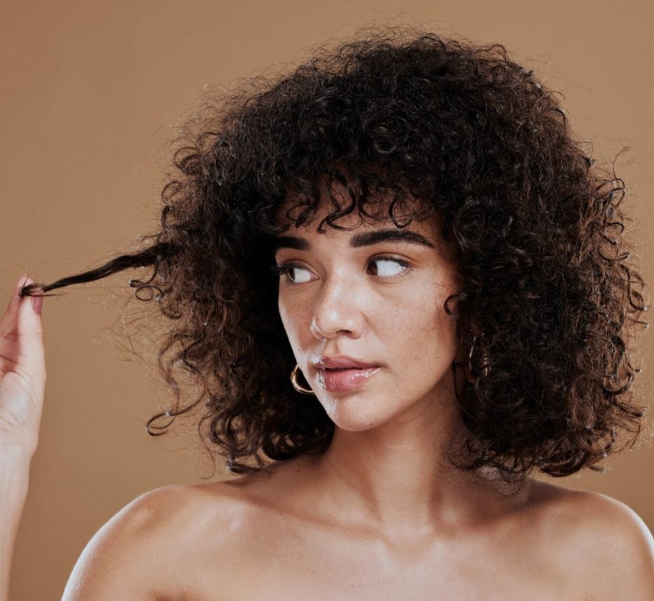 tóc xù tóc xù châu Phi cô gái đang chạm vào tóc và liếc mắt nhìn