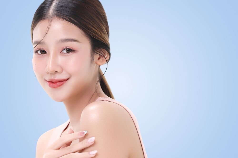 da thường cô gái cột tóc một đuôi với làn da sáng hồng nhìn vào ống kính cười mỉm