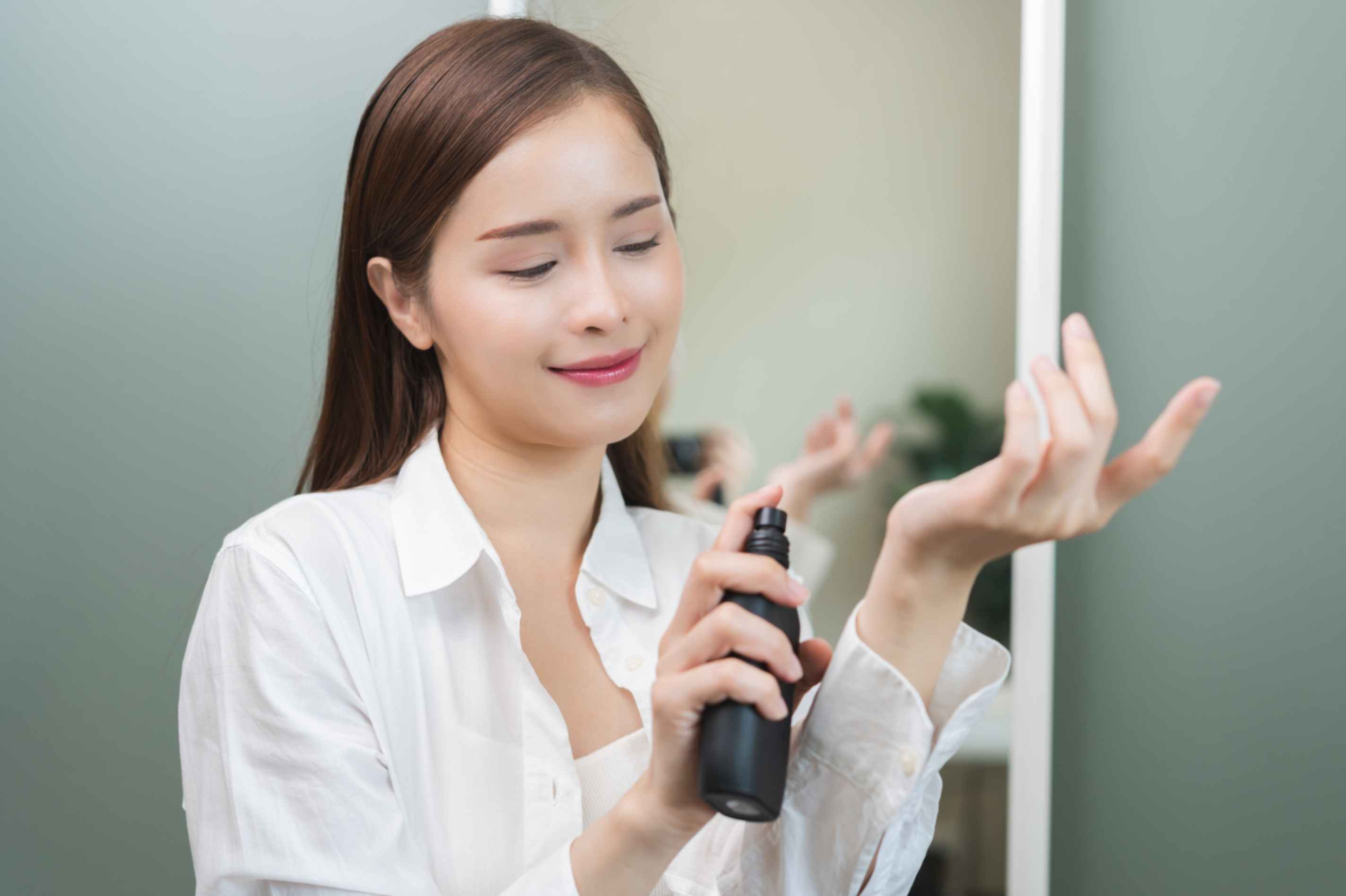 body mist là gì cô gái đang xịt bình xịt màu đen lên cổ tay