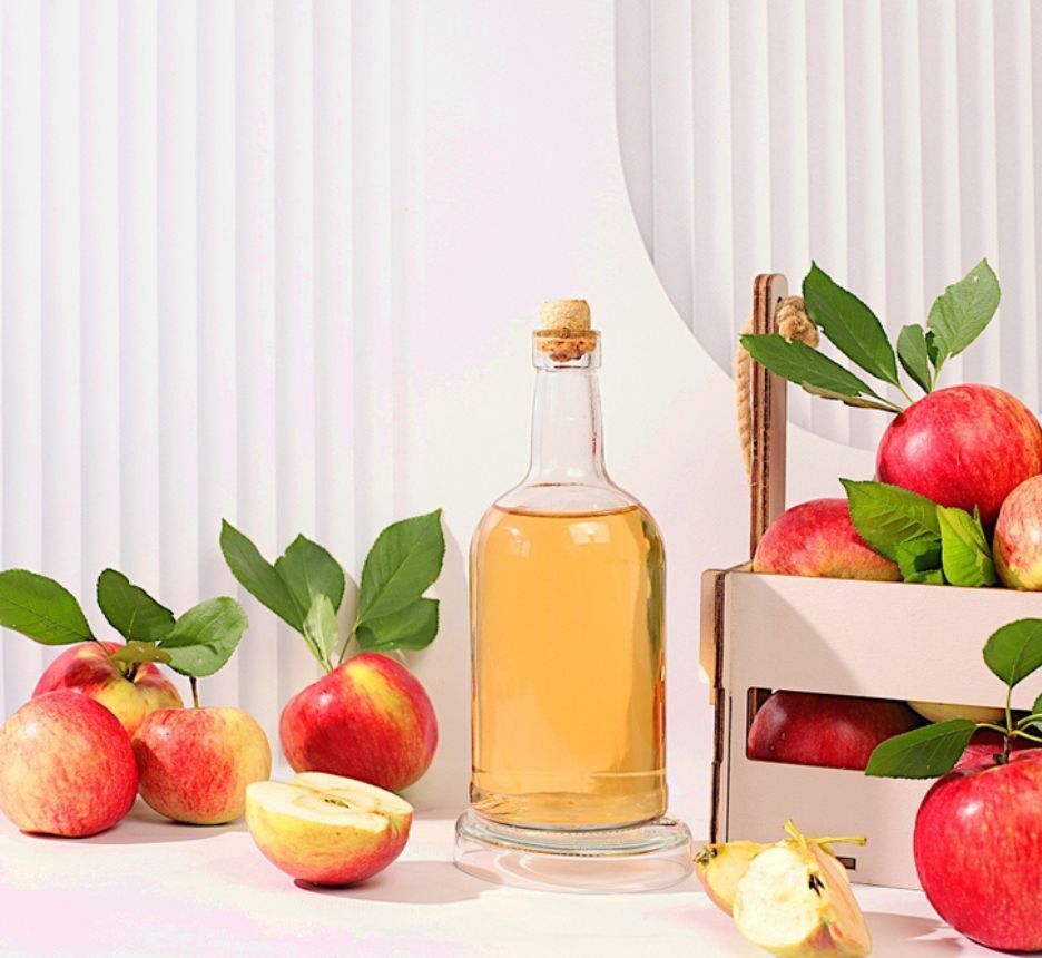 vảy nến da đầu ủ tóc với nguyên liệu tự nhiên chai đựng giấm táo đặt bên cạnh những quả táo chín đỏ