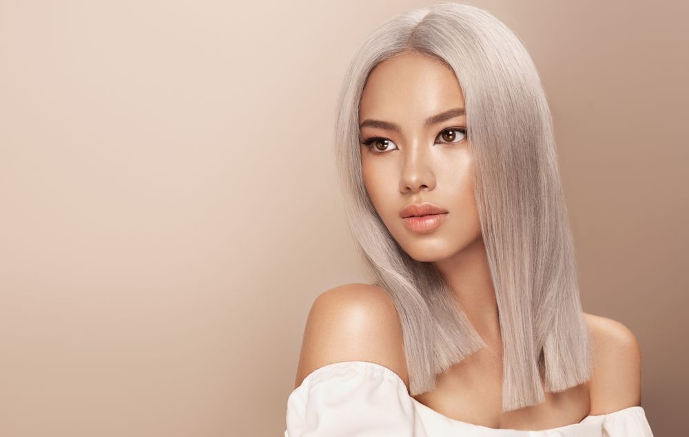 tẩy tóc cô gái có mái tóc màu bạch kim ép thẳng