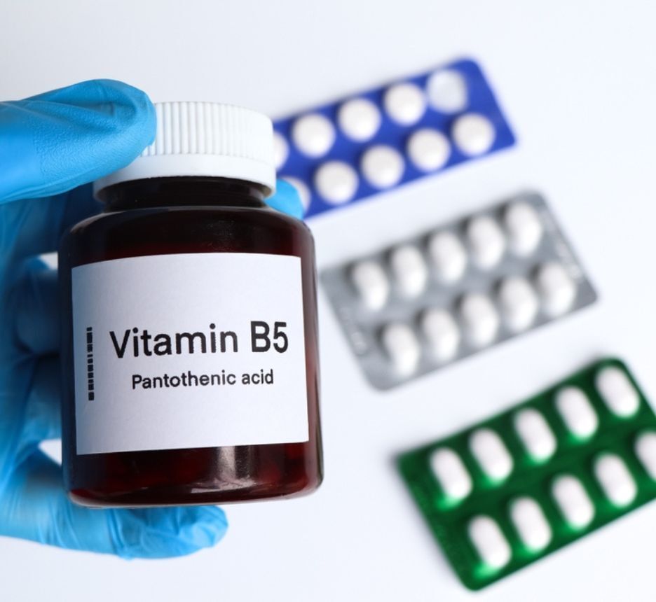 vitamin b5 có tác dụng gì vitamin B5 là gì cho tóc bàn tay đeo găng tay màu xanh cầm lọ thuốc dán nhãn Vitamin B5