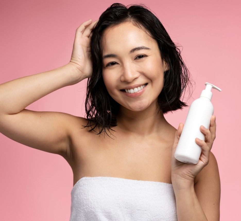 vitamin b5 có tác dụng gì cho tóc sử dụng sản phẩm chứa Vitamin B5 cô gái có mái tóc ướt đang cầm chai nhựa màu trắng