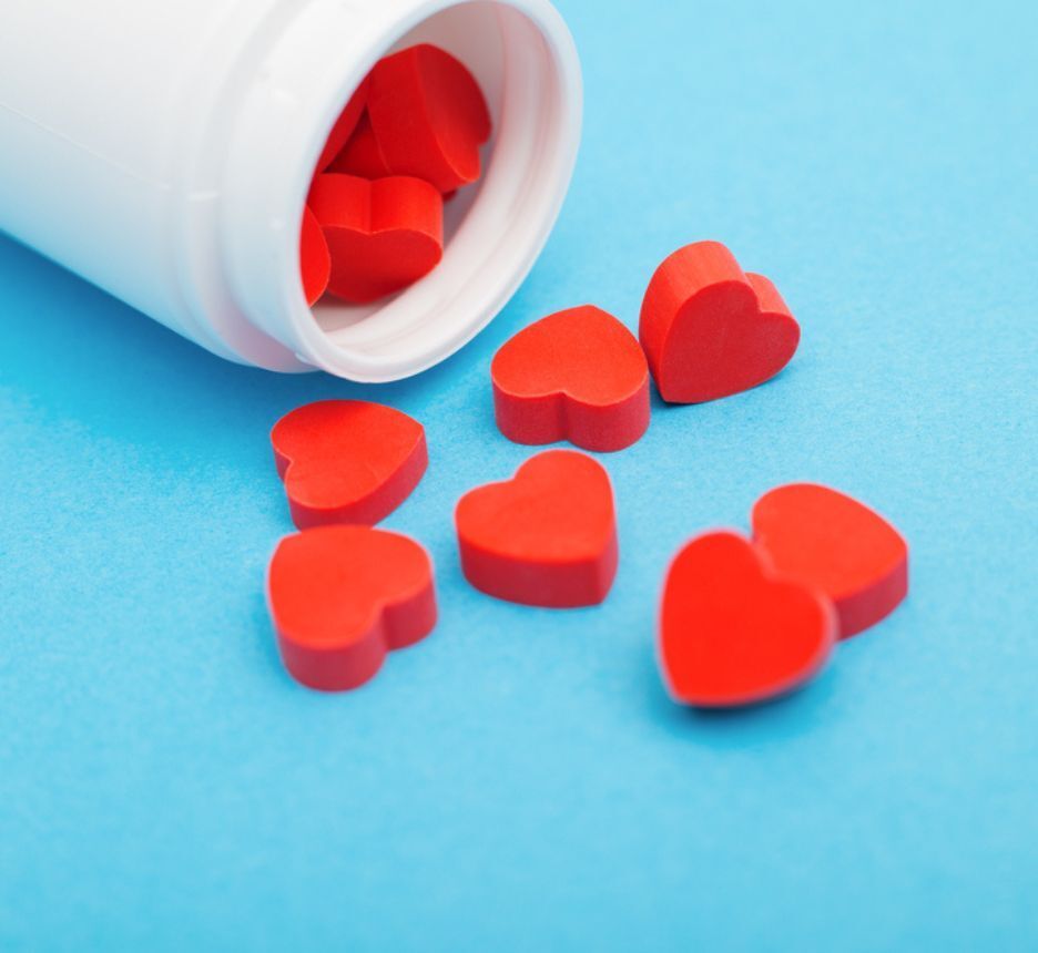 hormone hạnh phúc oxytocin là gì hủ thuốc màu trắng với các viên thuốc hình trái tim màu đỏ trên nền xanh biển.