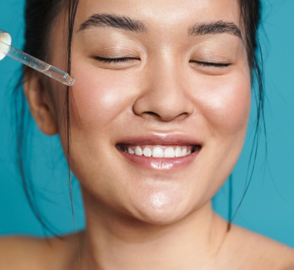 dầu dưỡng da lợi ích của dầu dưỡng da cô gái cười tươi đang nhỏ dầu dưỡng lên gò má