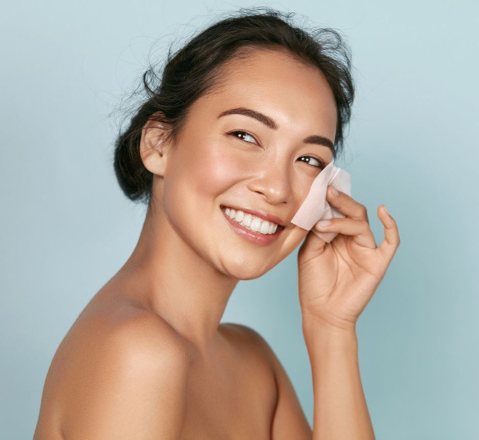 dầu dưỡng da chọn dầu dưỡng phù hợp với loại da cô gái cầm giấy thấm dầu áp lên má và cười tươi