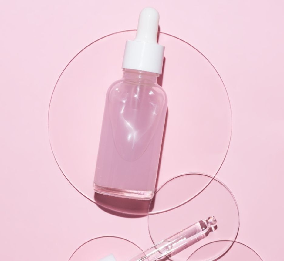 dầu dưỡng da kết hợp với serum đặc trị chai serum đặt trên nền hồng
