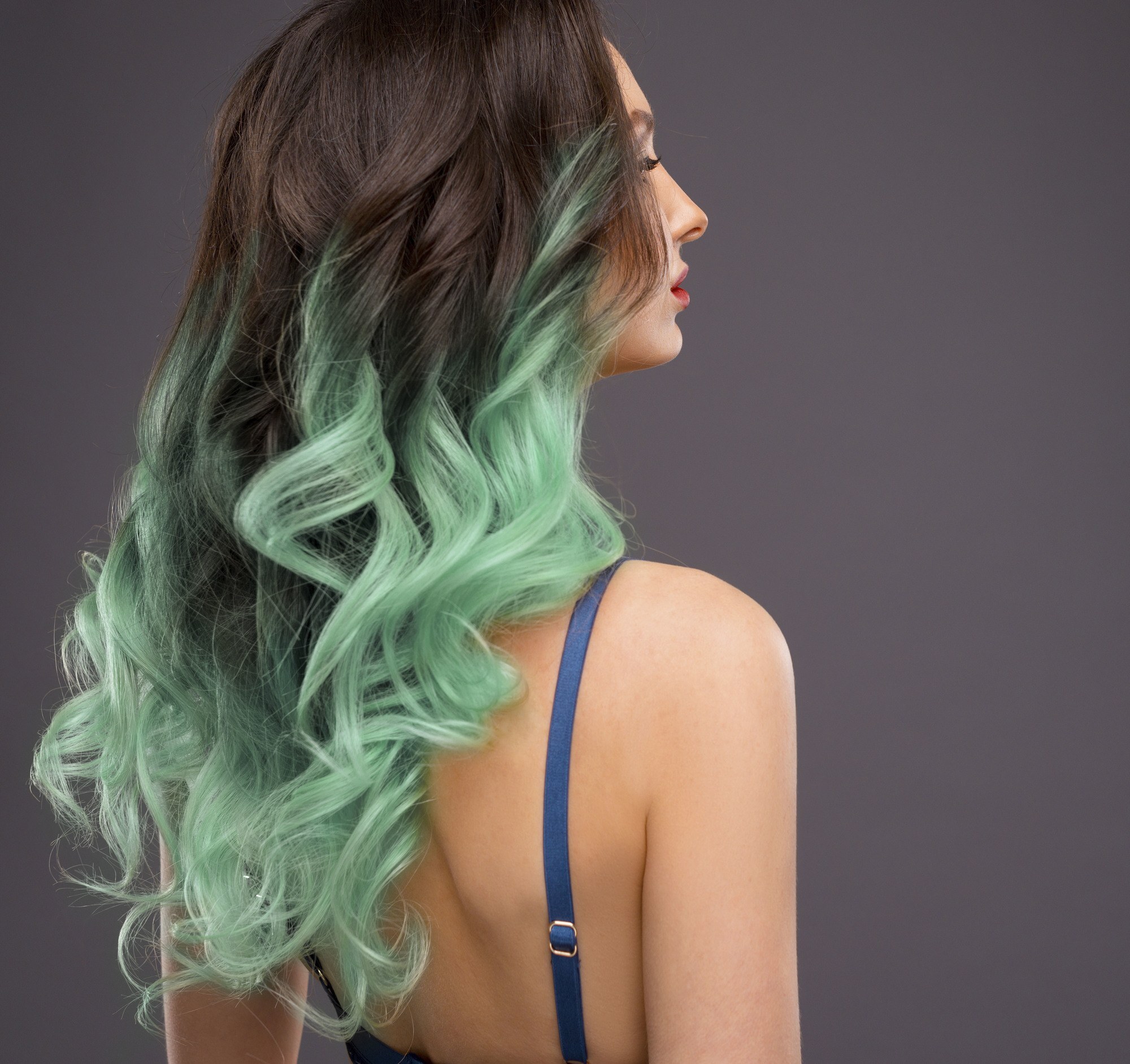 woman with long green ombre hair dark roots wavy hair