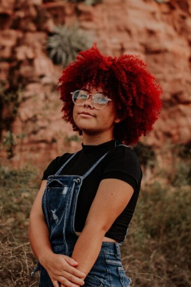 woman with voluminous natural curls, dyed a bold red colour