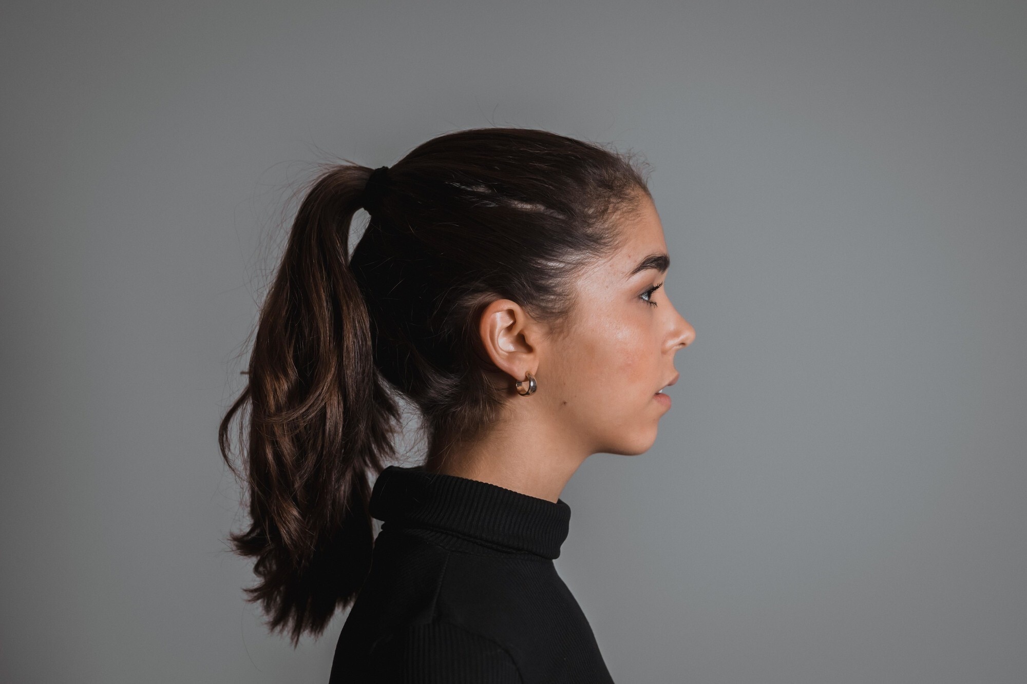 Engagement hairstyle: woman with dark brown hair wearing a sleek ponytail