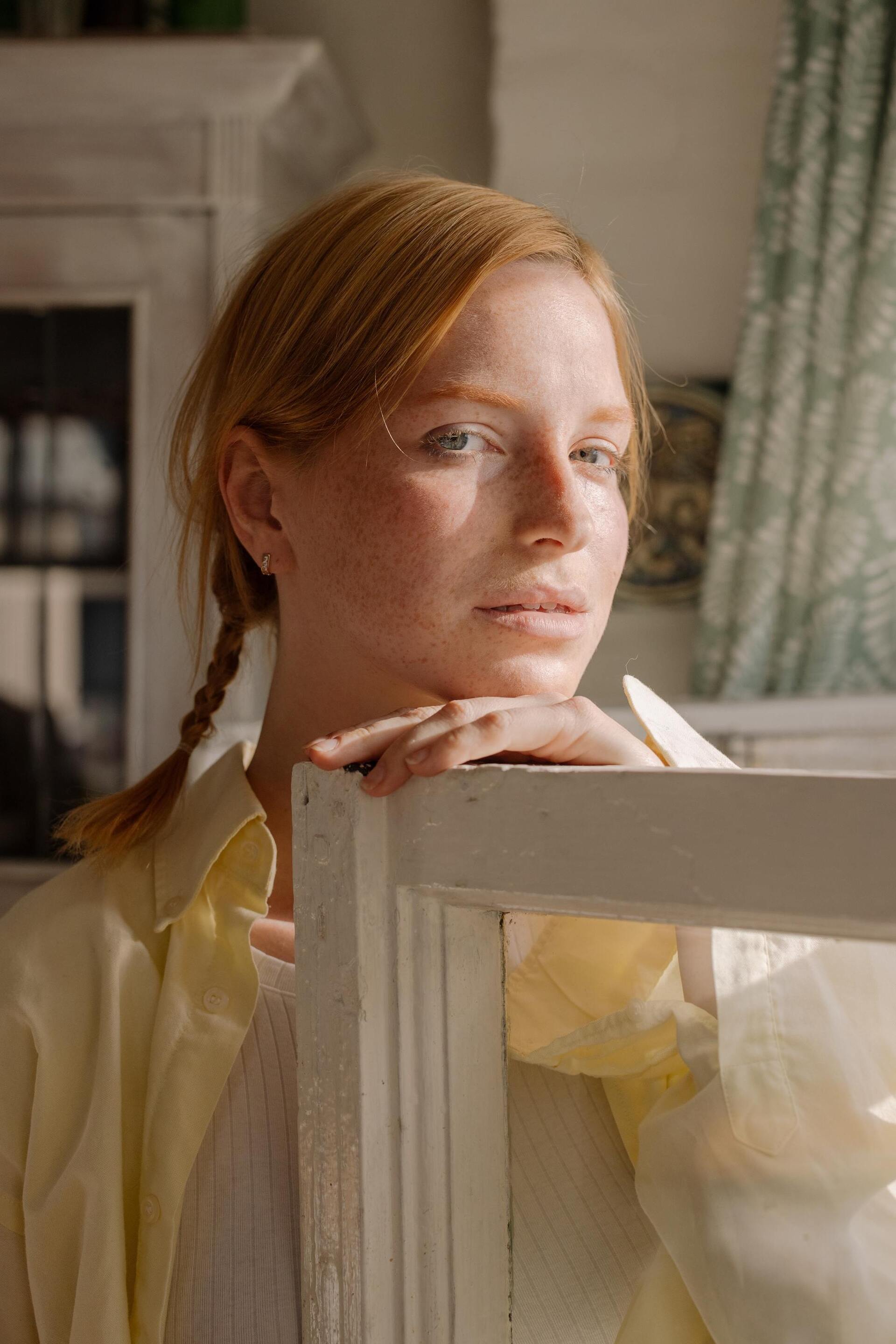 Euphoria hairstyles: woman with ginger hair, tied into two low, braided ponytails