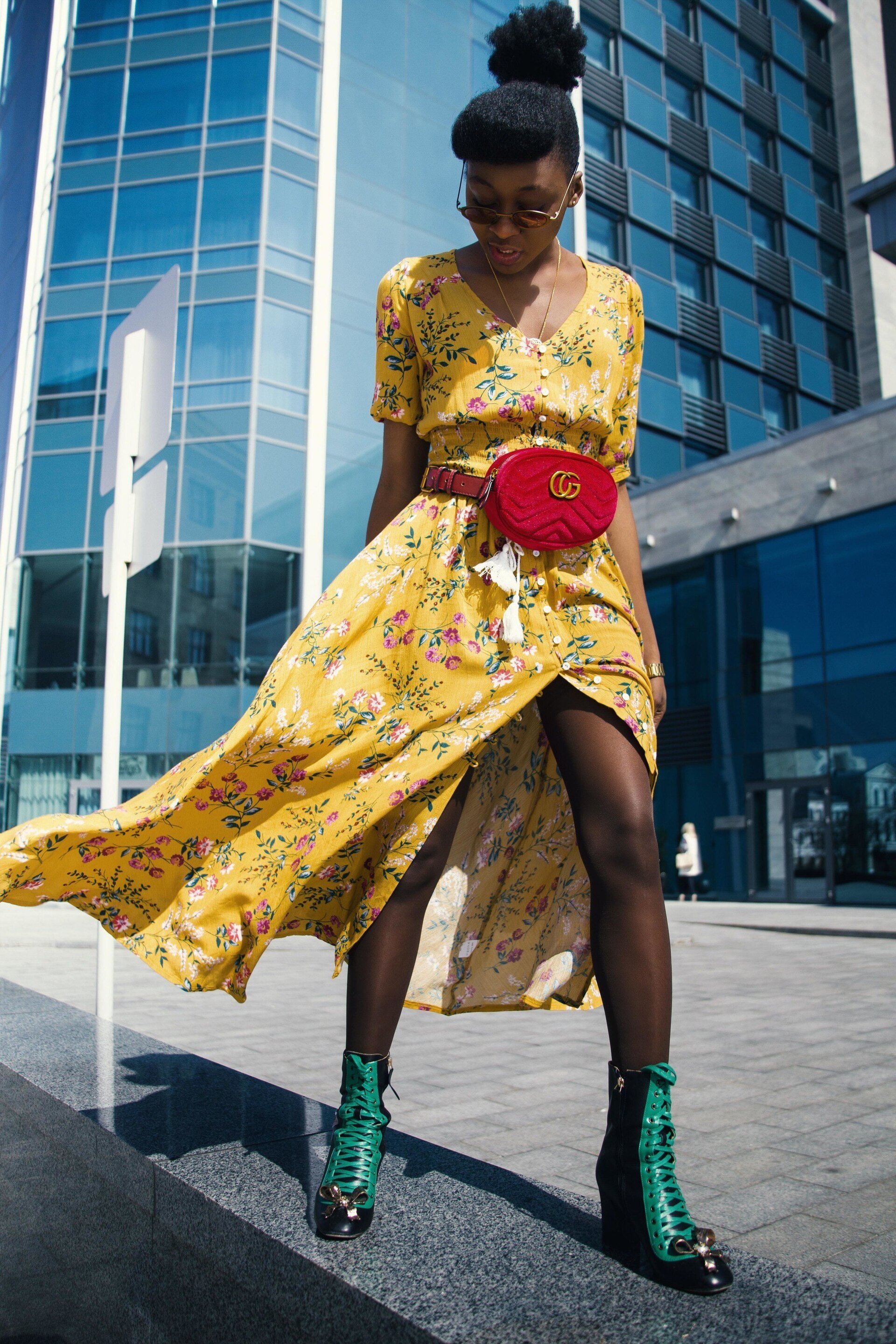 woman with a bold yellow dress and an her hair tied into a high puff updo with a rolled fringe