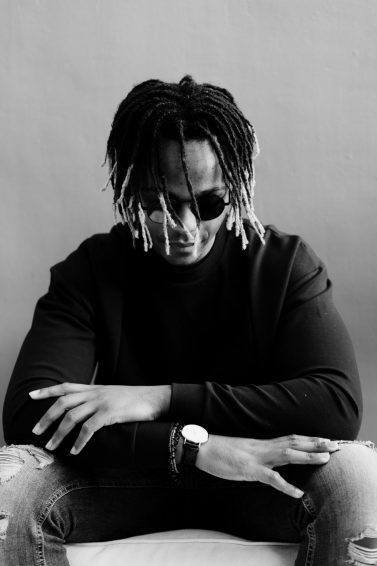 hair stories: black and white image of a man with medium-length locs with blonde tips