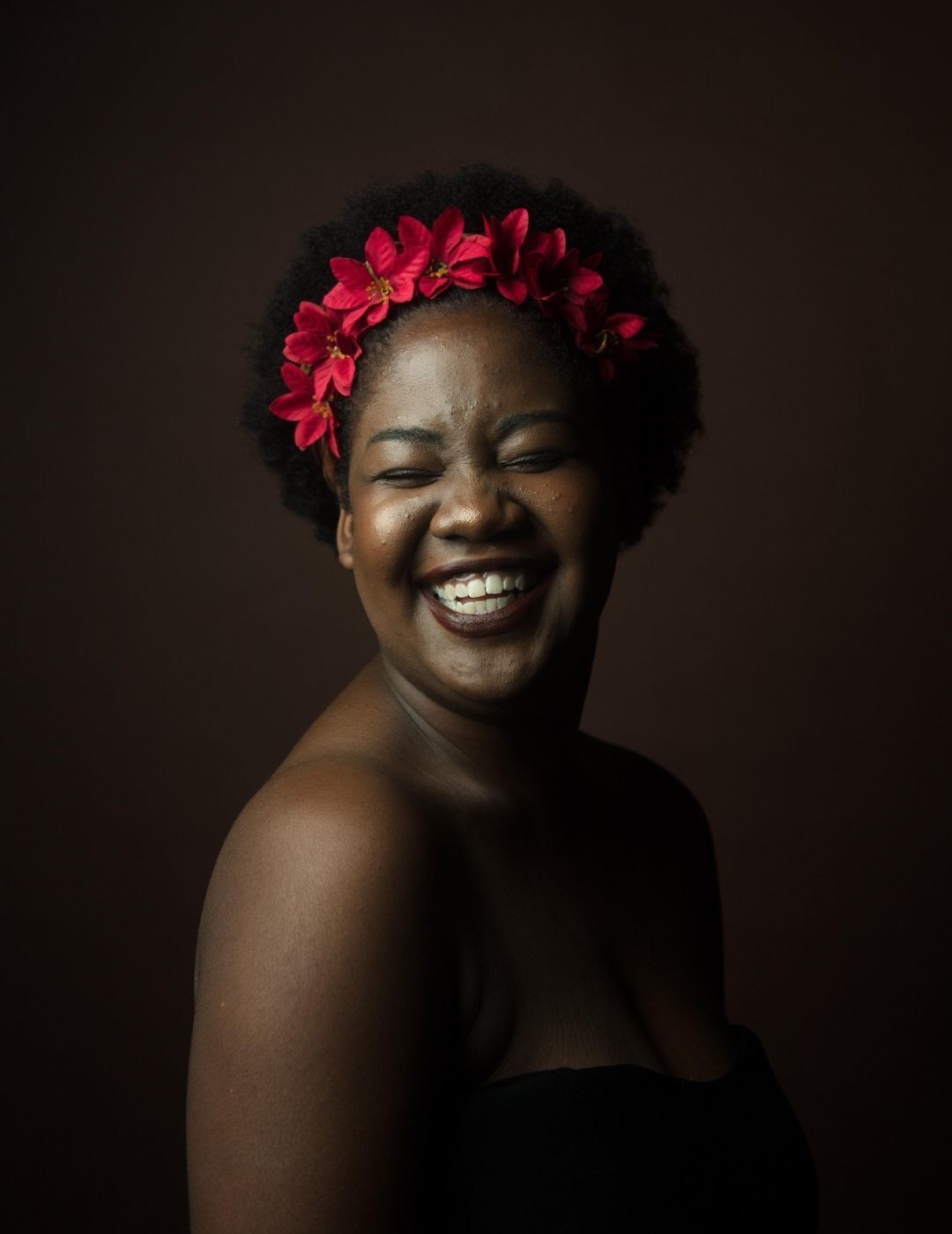 world afro day: woman with afro hairstyle wearing a large red flower crown accessory