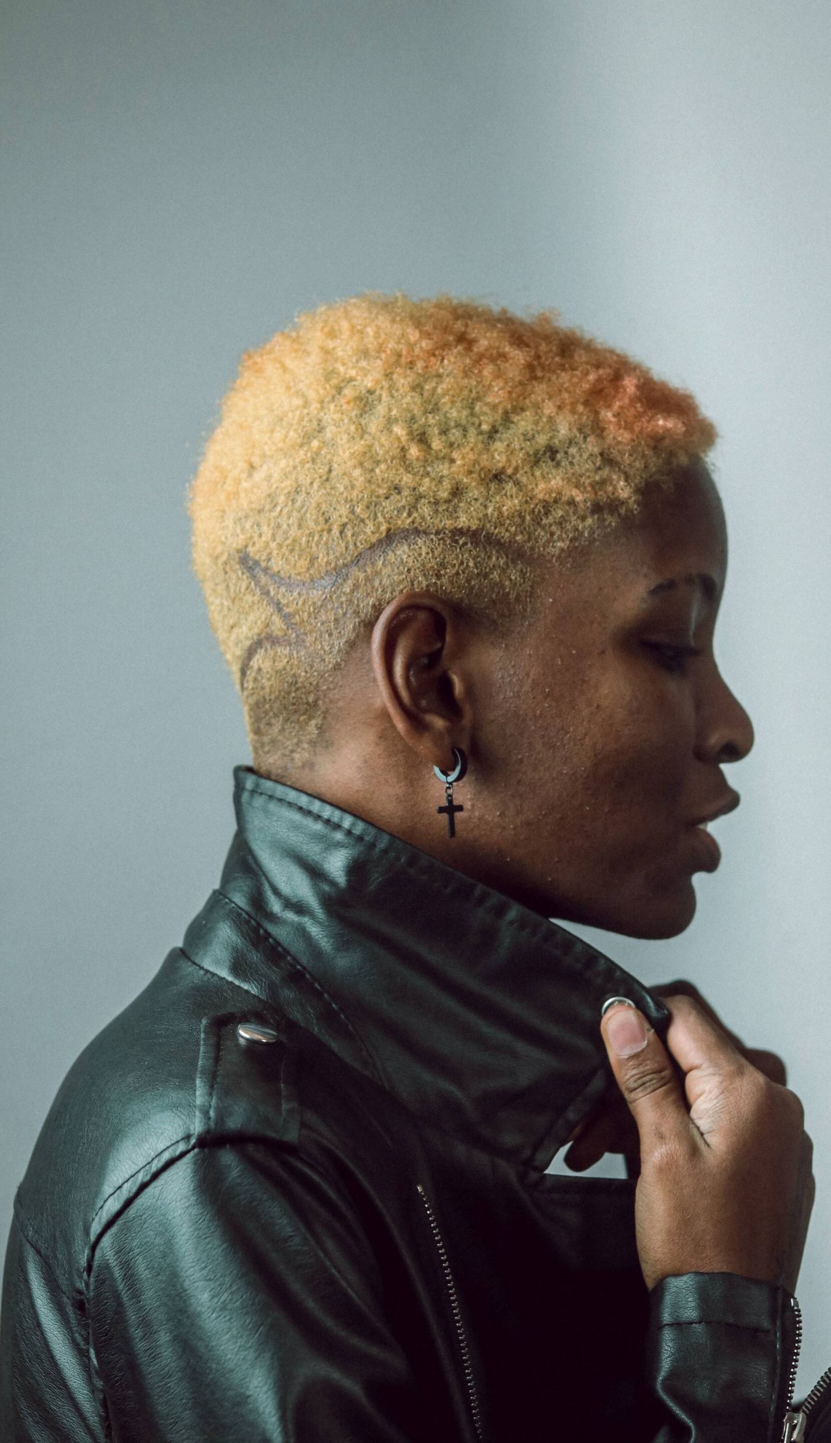 woman with a short, blonde afro hairstyle, with a shaved design on the side