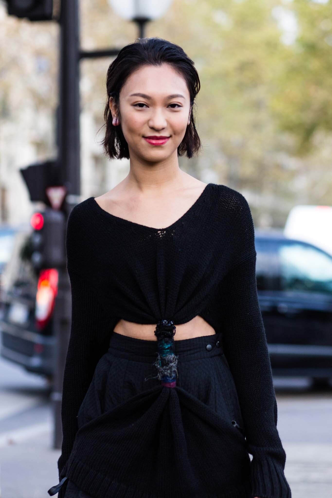 Woman with dark brown swept back bob wearing a all black outfit.