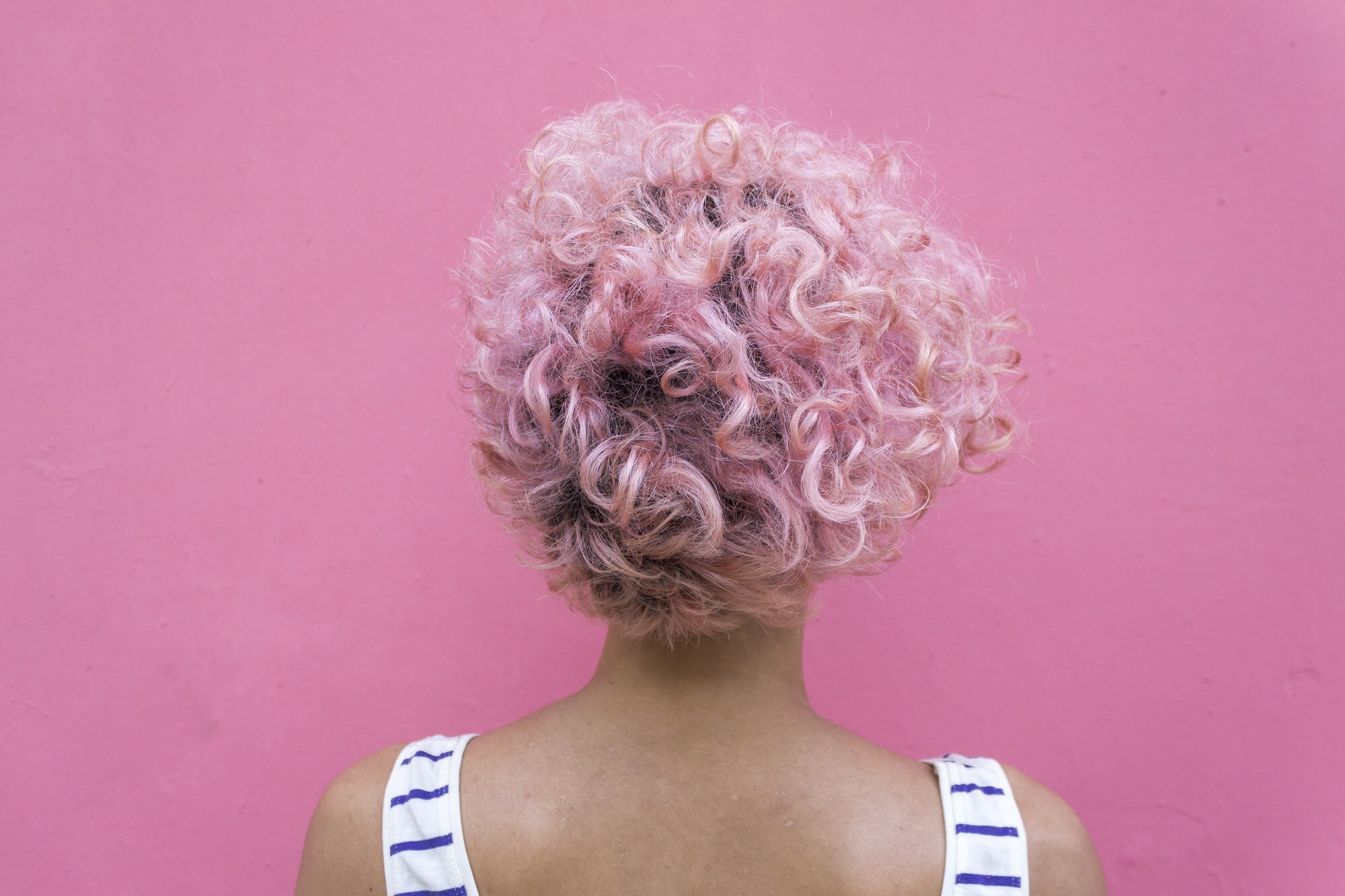 woman with short pink permed hair and dark roots