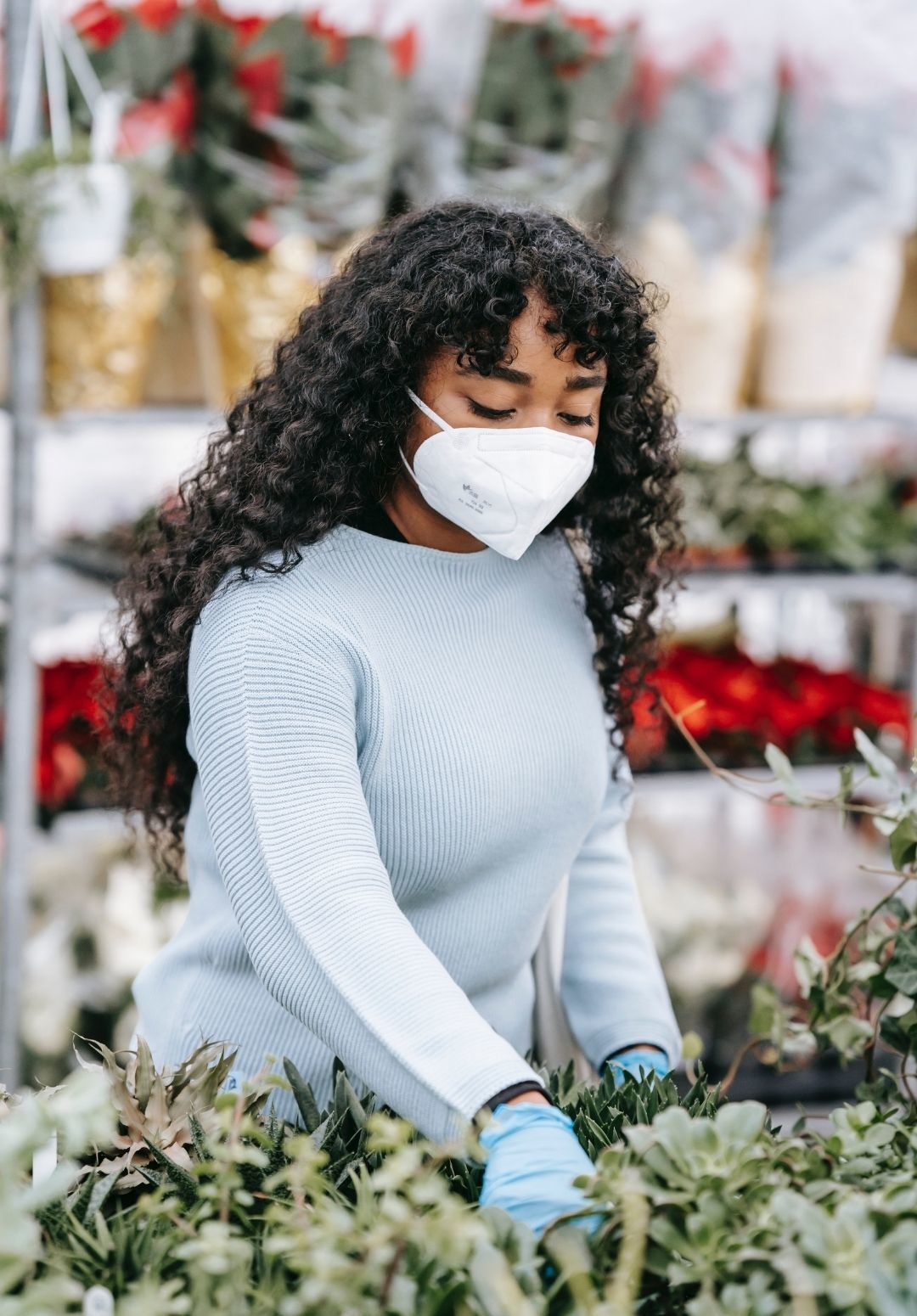 2022 hair trends : image of a woman wearing a white face mask, with long naturally curly brown hair