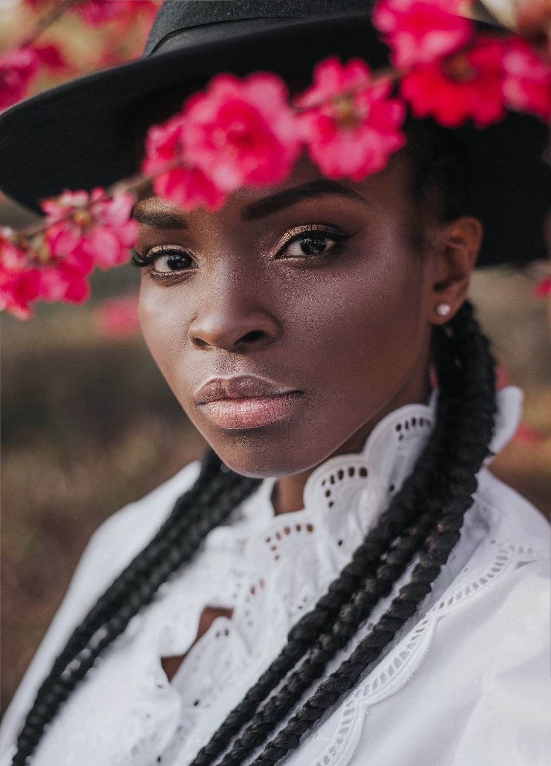 woman with long cornrows and a hat