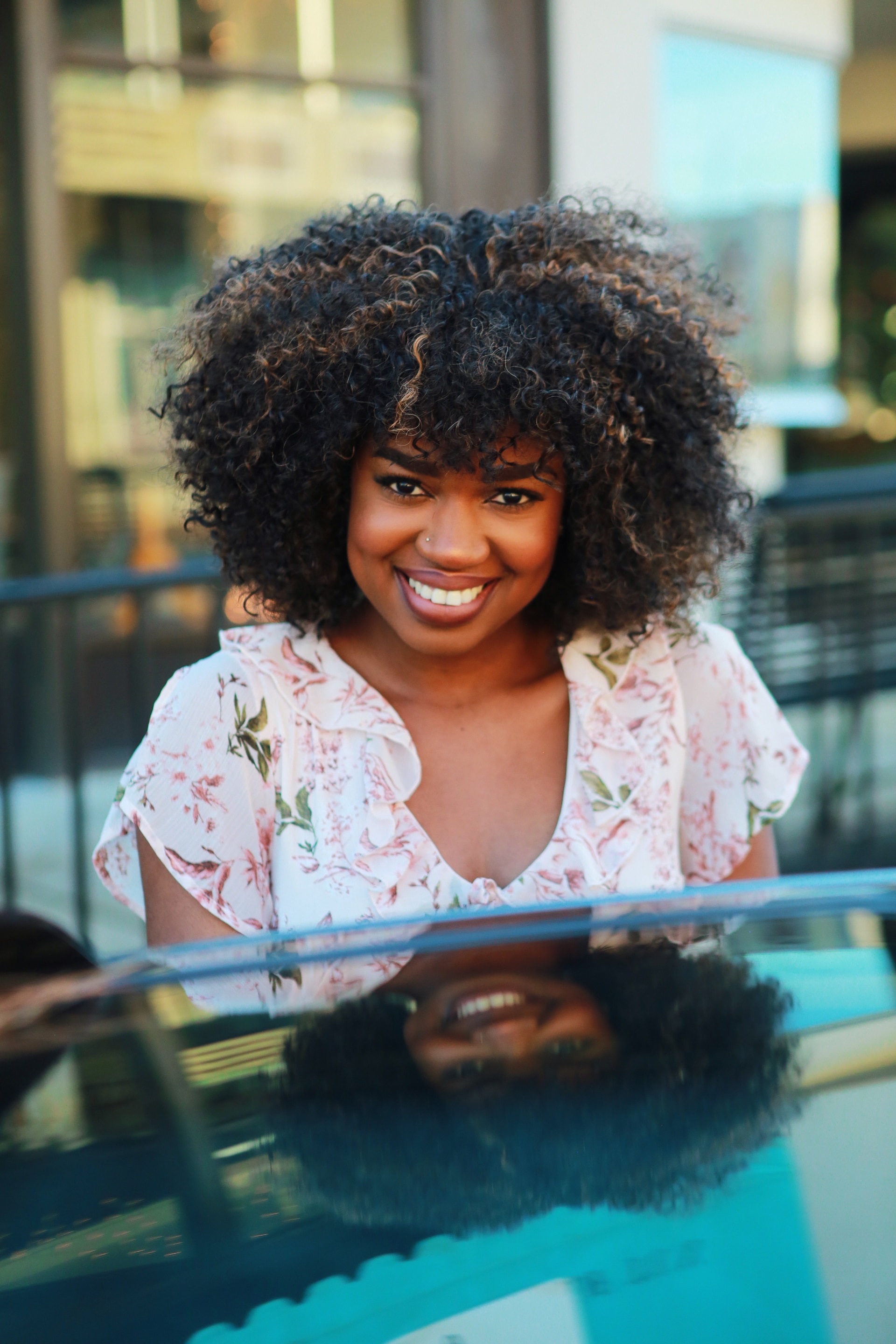 smiling lady with big afro natural hair curls brown highlights