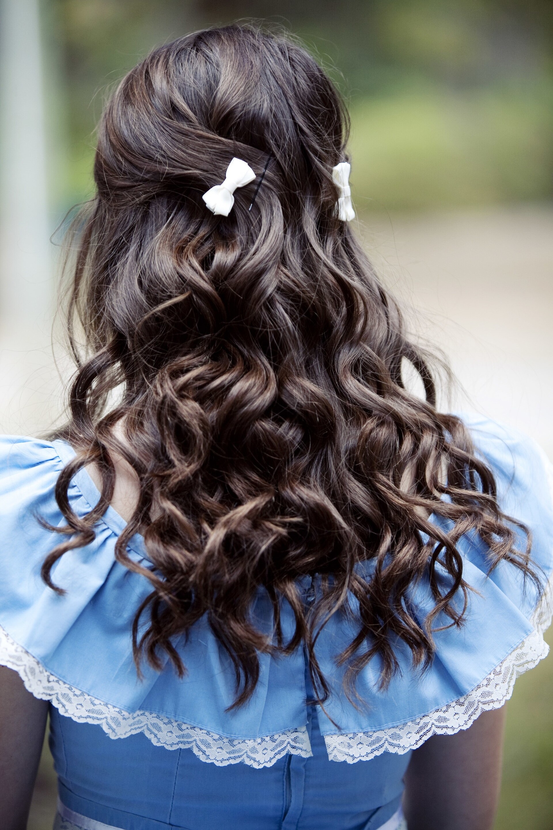 spring-worthy hairstyles: woman with brown wavy hair, wearing little white bow accessories