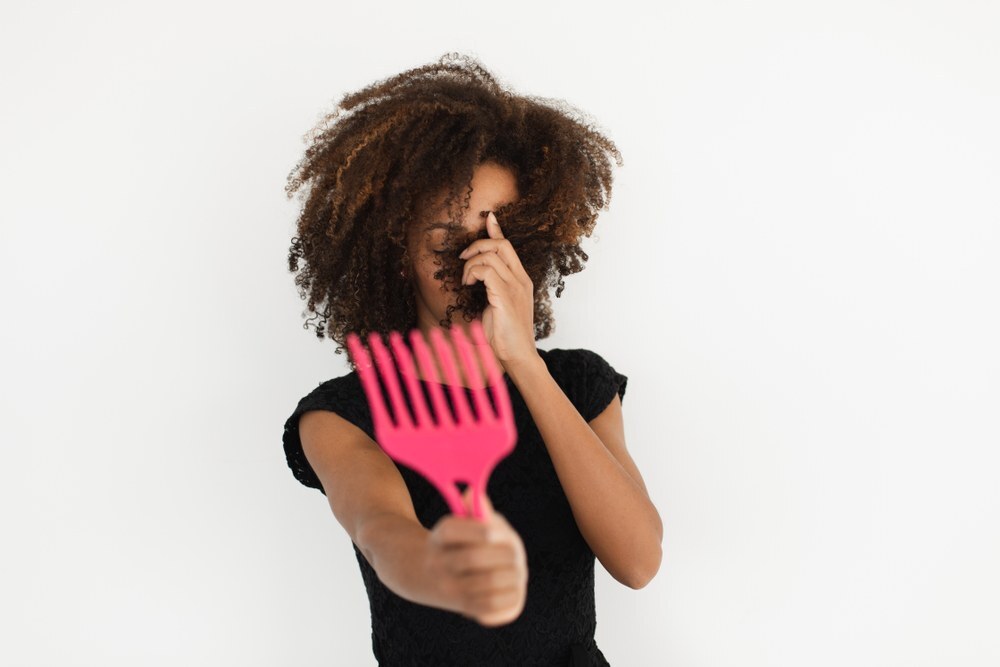 woman with natural hair holding a comb