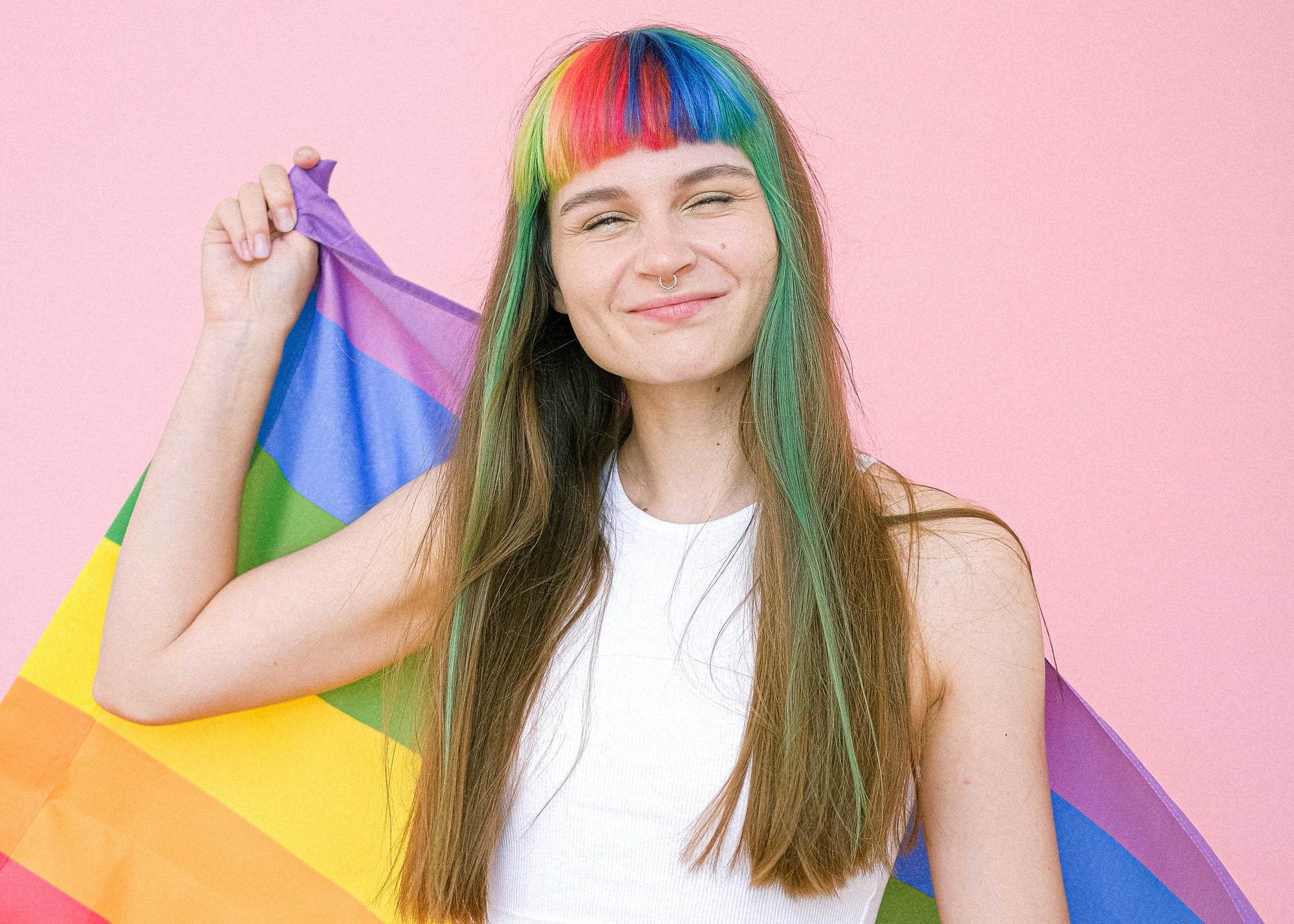 Pride: woman with rainbow fringe and long brown hair holding a pride flag