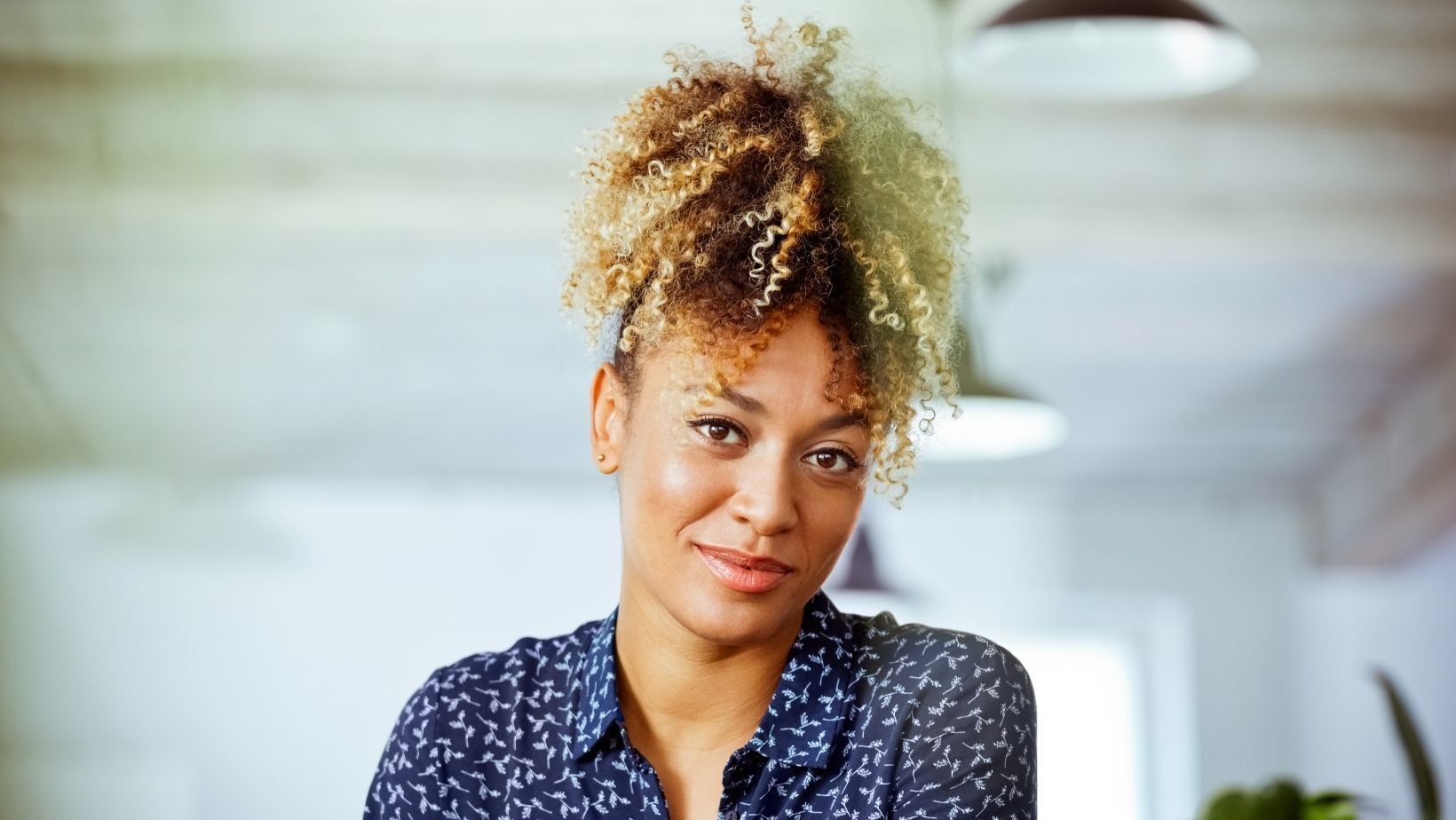 Woman with blonde and brown curly hair tied up