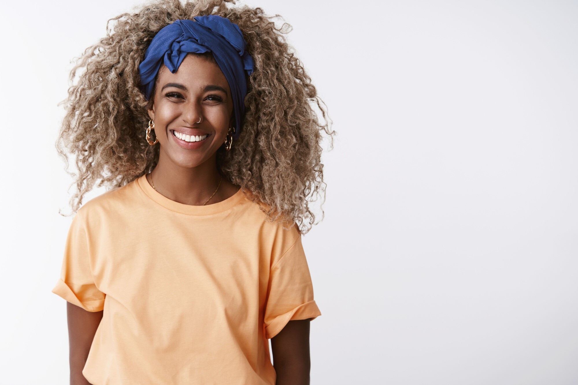 woman with long ash blonde curly hair and blue head scarf