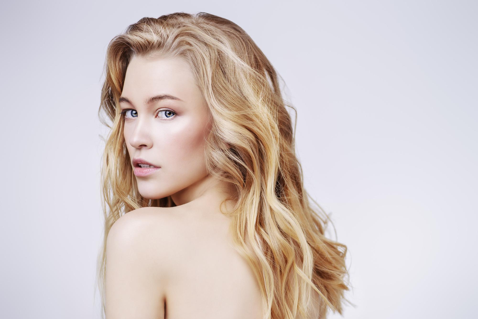 damage caused by styling woman long wavy hair blonde hair