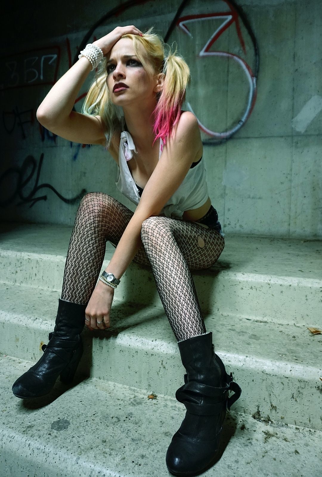 halloween hairstyle: woman dressed in a Harley Quinn outfit, with two blond ponytails and colourful ends