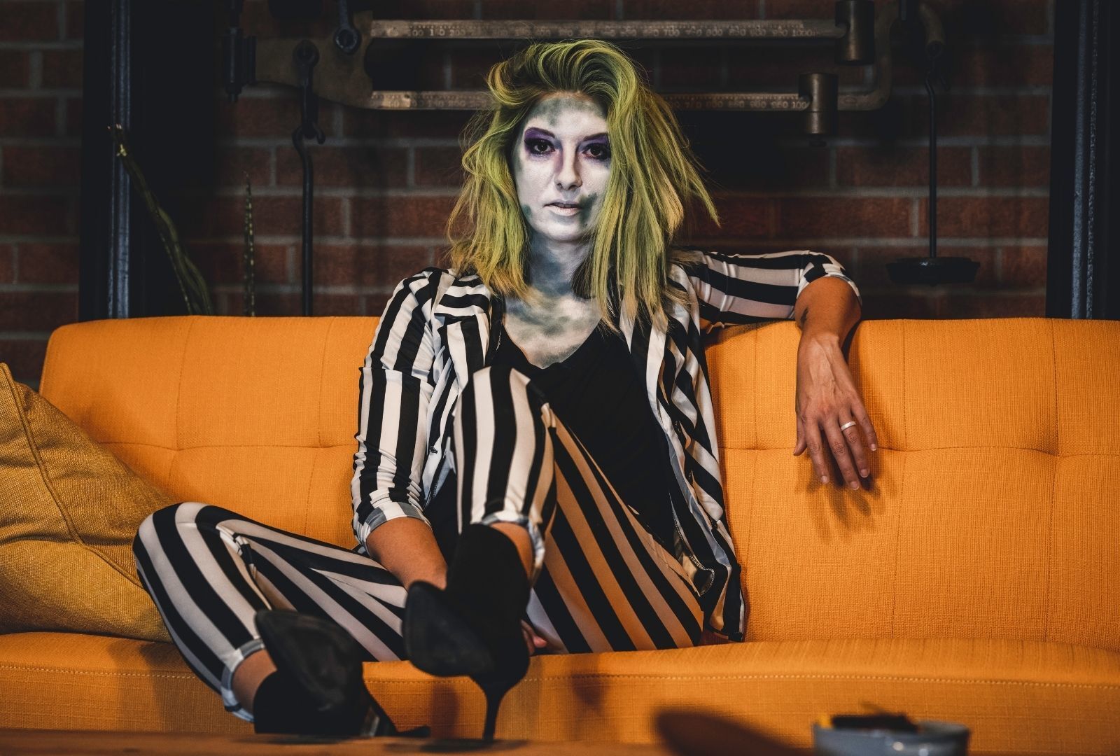 halloween hairstyle: woman wearing a black and white striped suit with wavy green hair