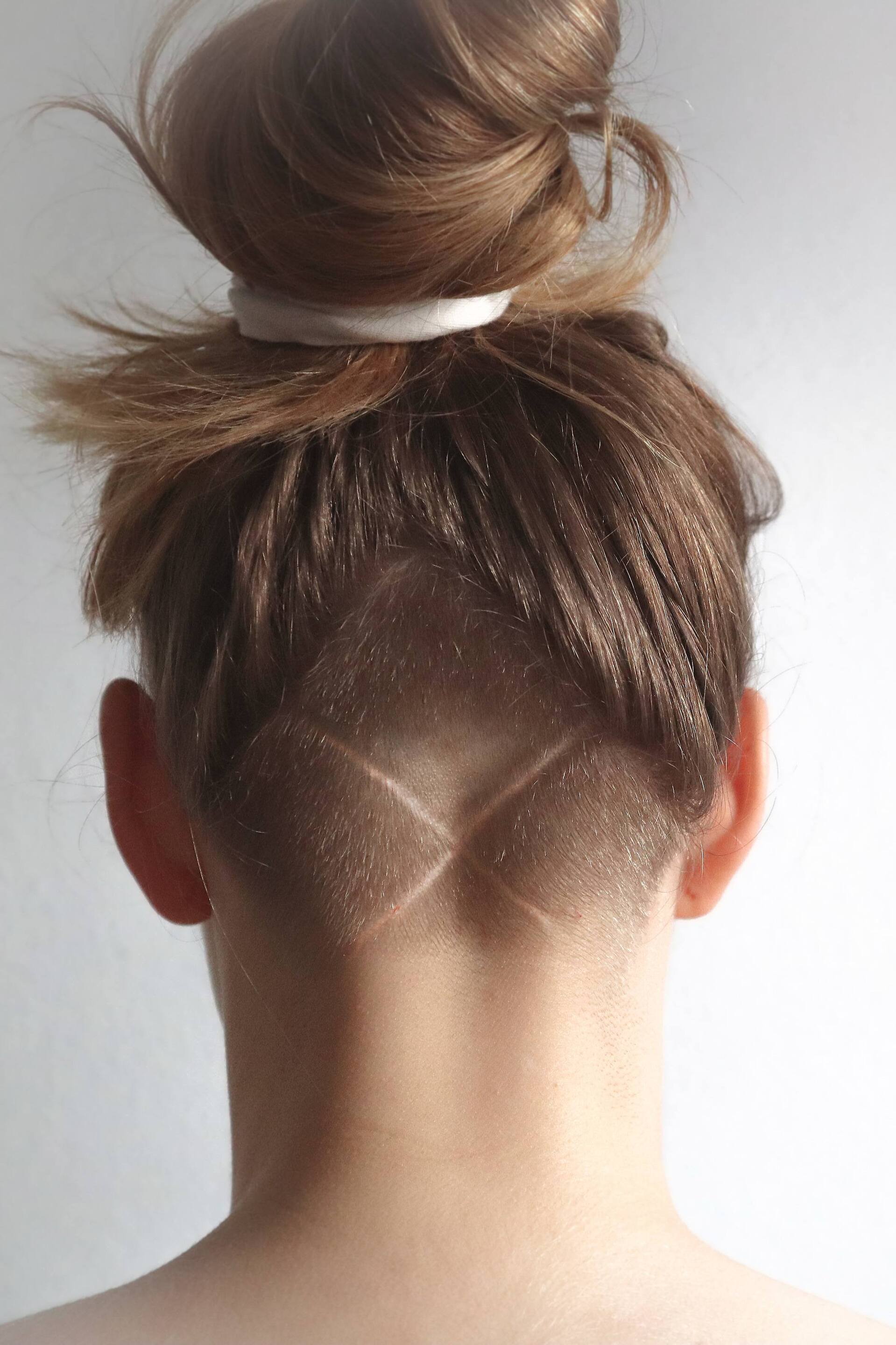 undercut hairstyle with long light brown hair tied in a bun