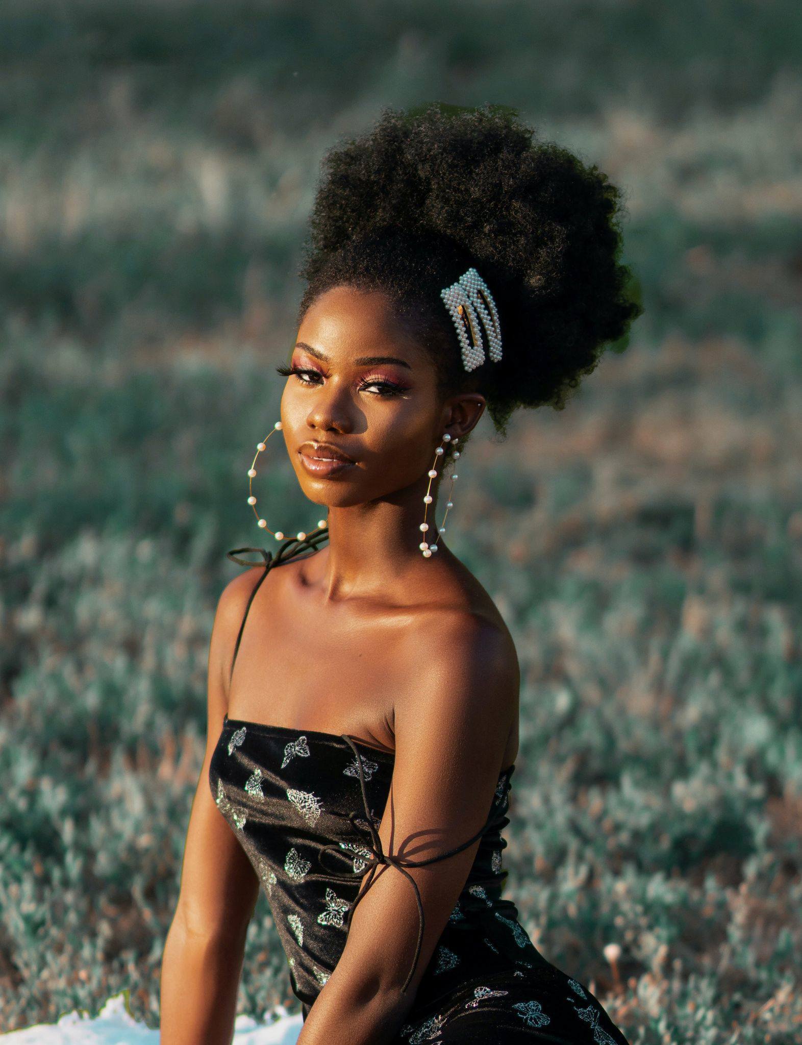 Cancer zodiac: woman with natural hair tied up into a high puff hairstyle with oversized pearl clip-on hair accessories