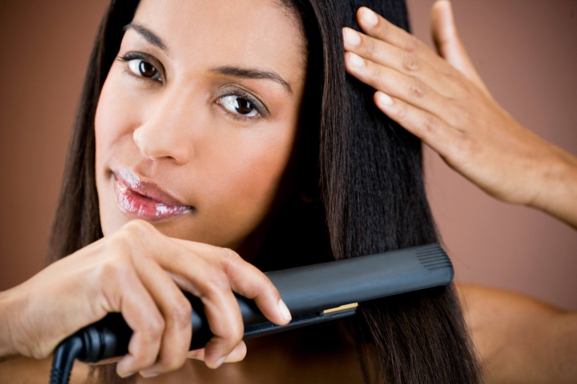 woman heat styling her hair with a flat iron