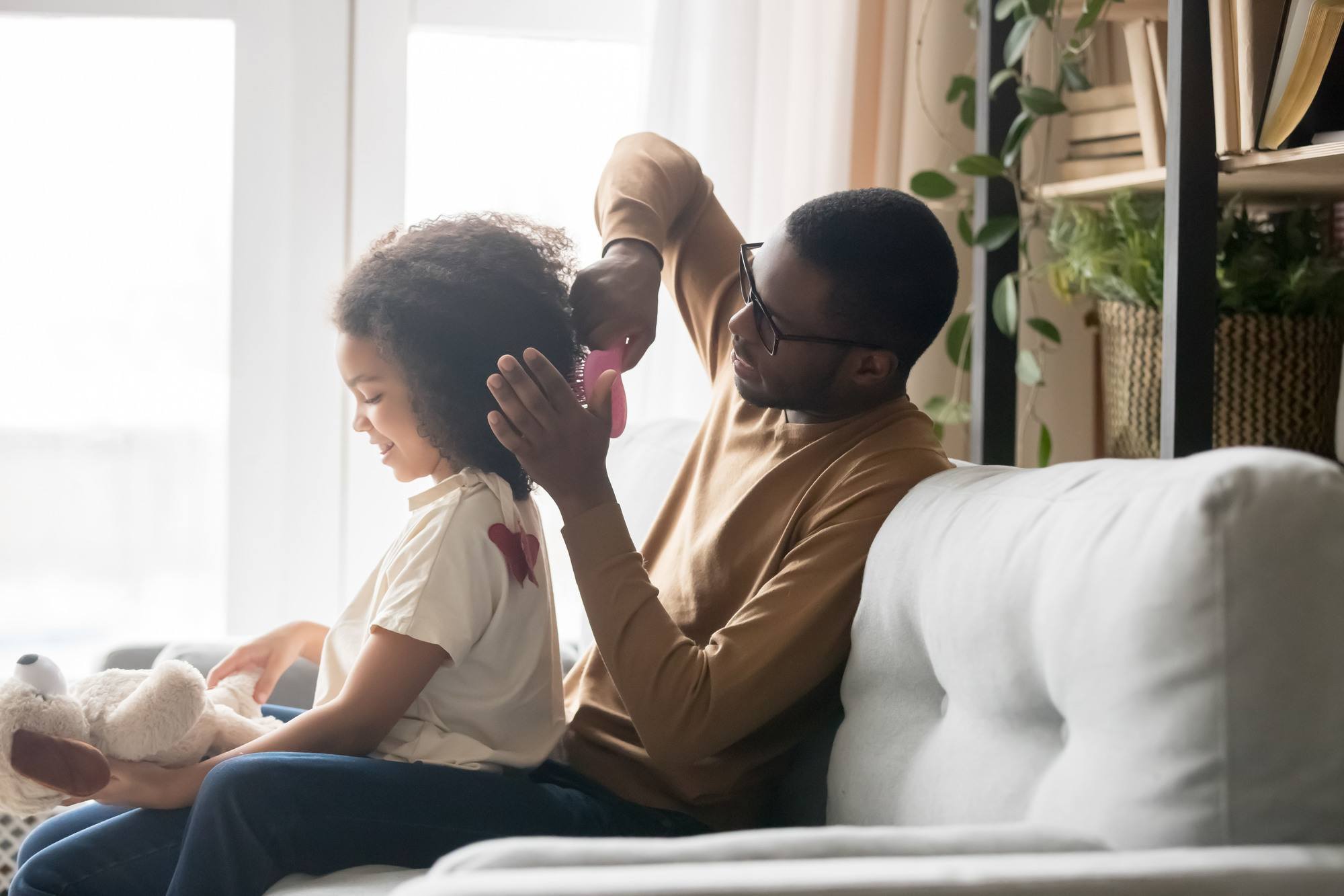for your and the kids: a father brushing his daughter's naturally curly hair with a pink detangling brush
