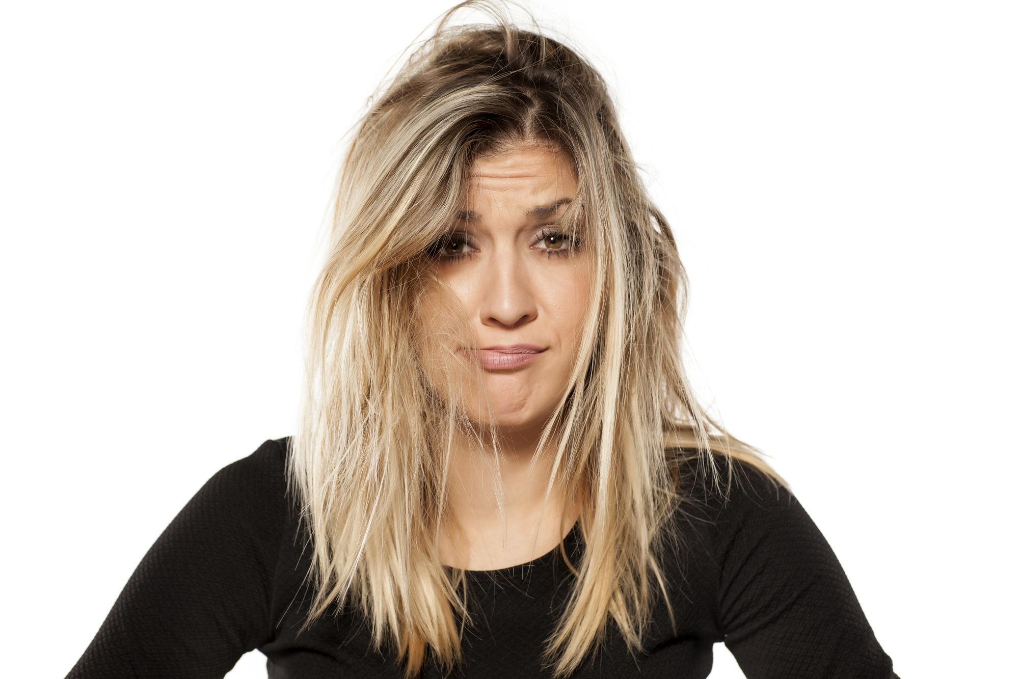 woman with messy blonde hair and dark roots