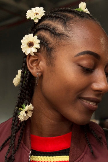 Cornrows: Woman at AfroPunk with hair in cornrow braids with sunflowers placed throughout her hair.