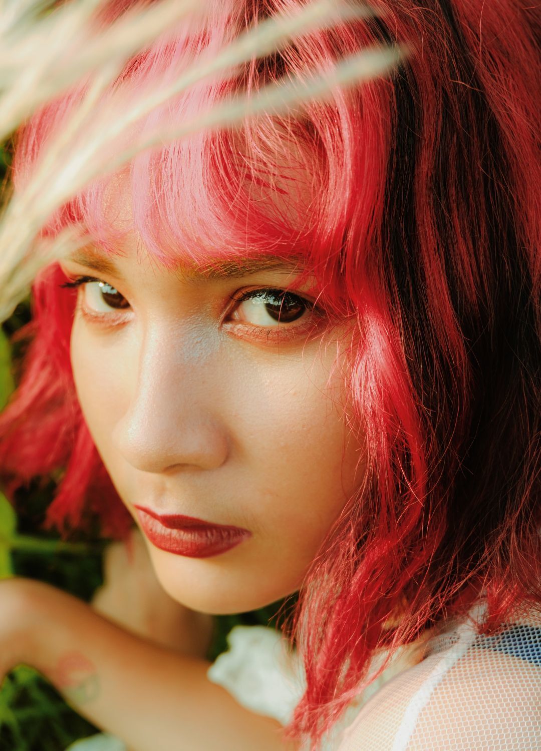 close-up shot of a woman with a wavy bob haircut with a fringe; hair dyed bright red with thick black streaks