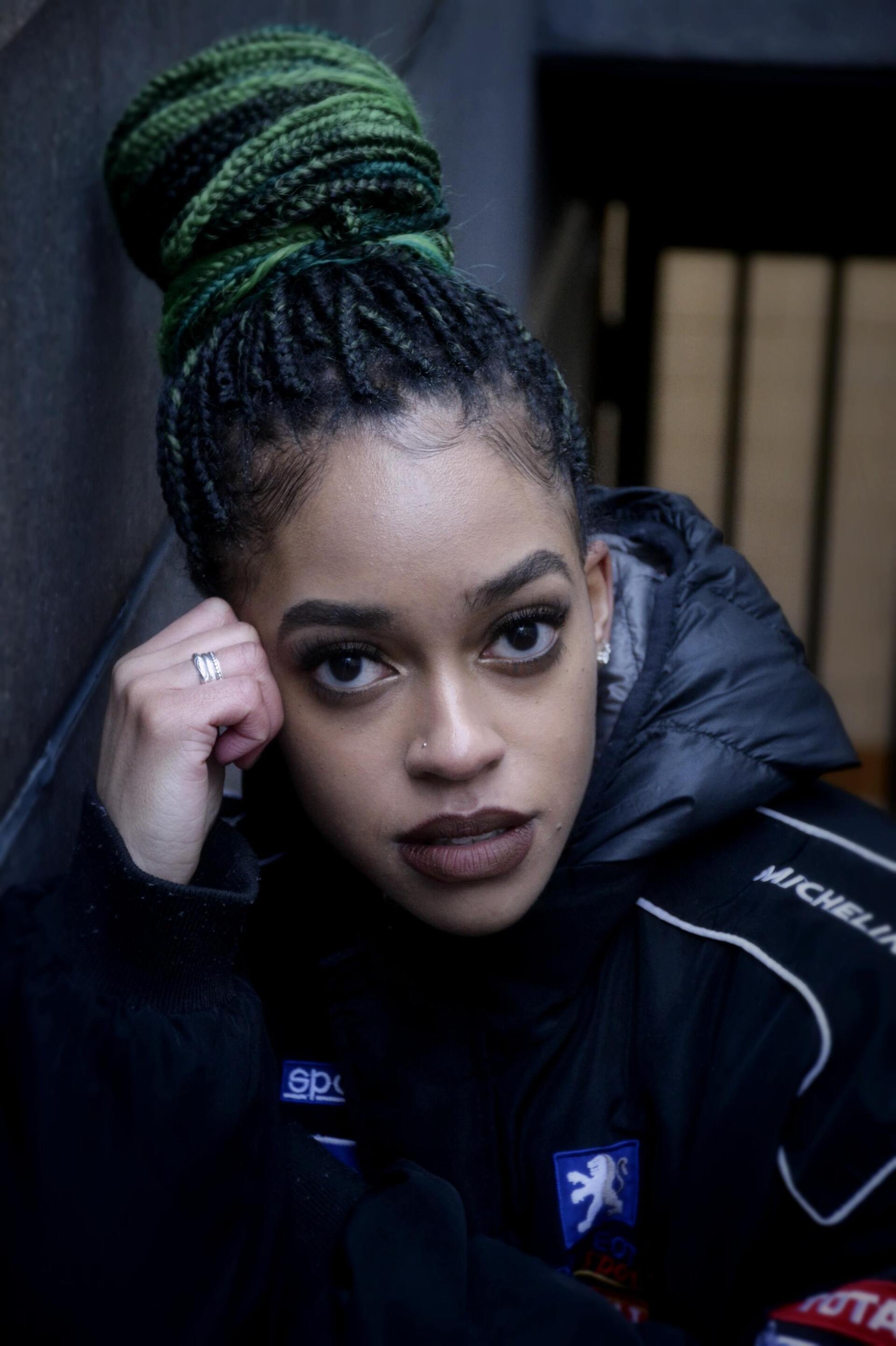 woman with green braids tied into a high bun hairstyle
