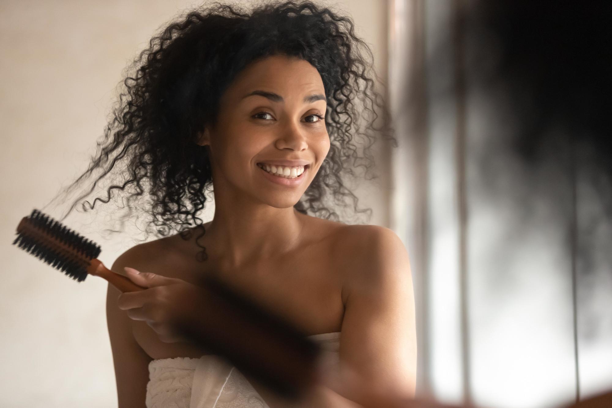 Woman with naturally curly hair and a brush