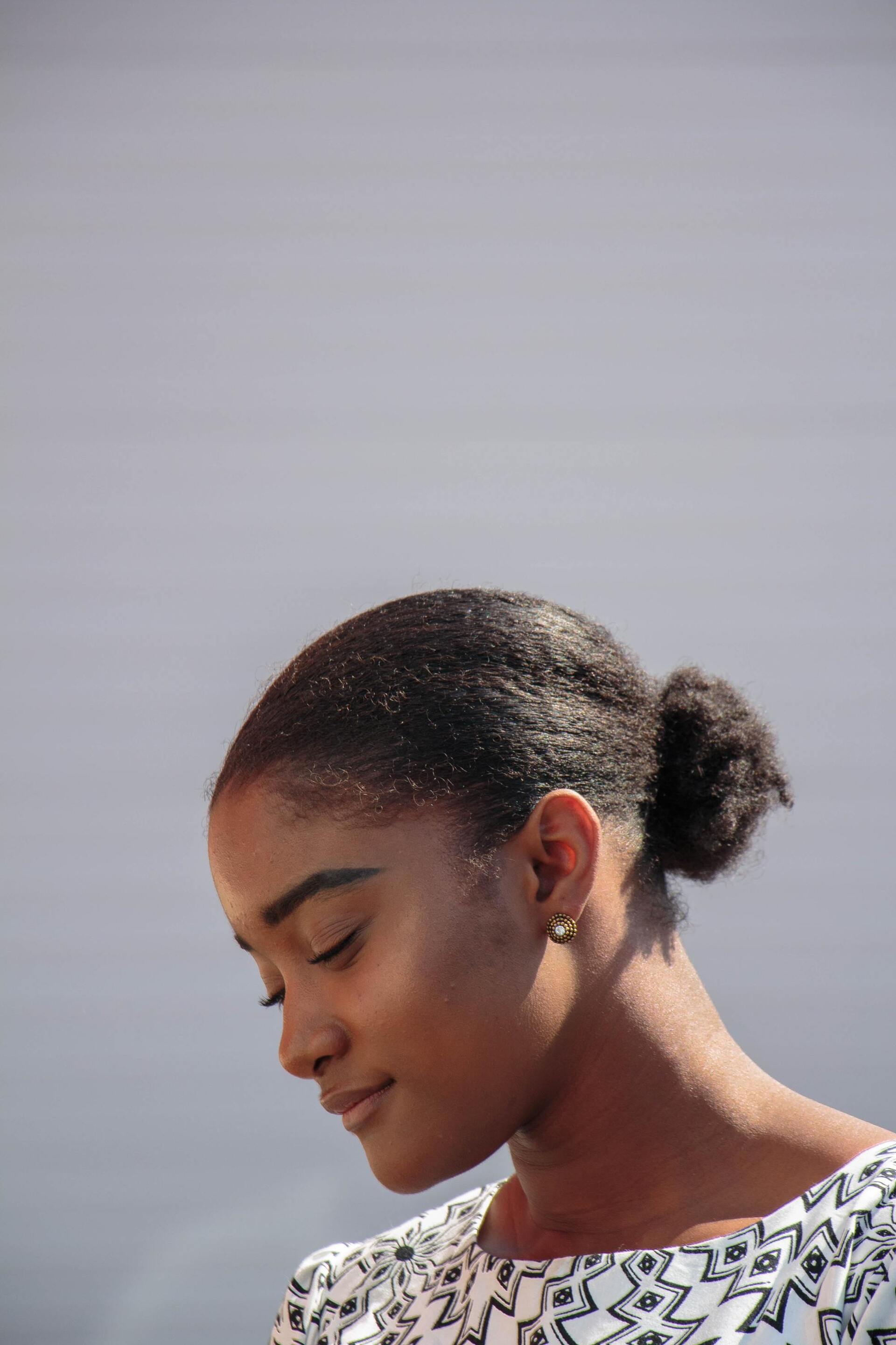 side profile shot of a woman with short natural hair, tied into a low puff